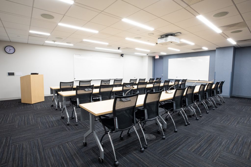 Conference Room 3A at One Rotary Place. Photo of a large conference room with tables & chairs, a podium, and a whiteboard.