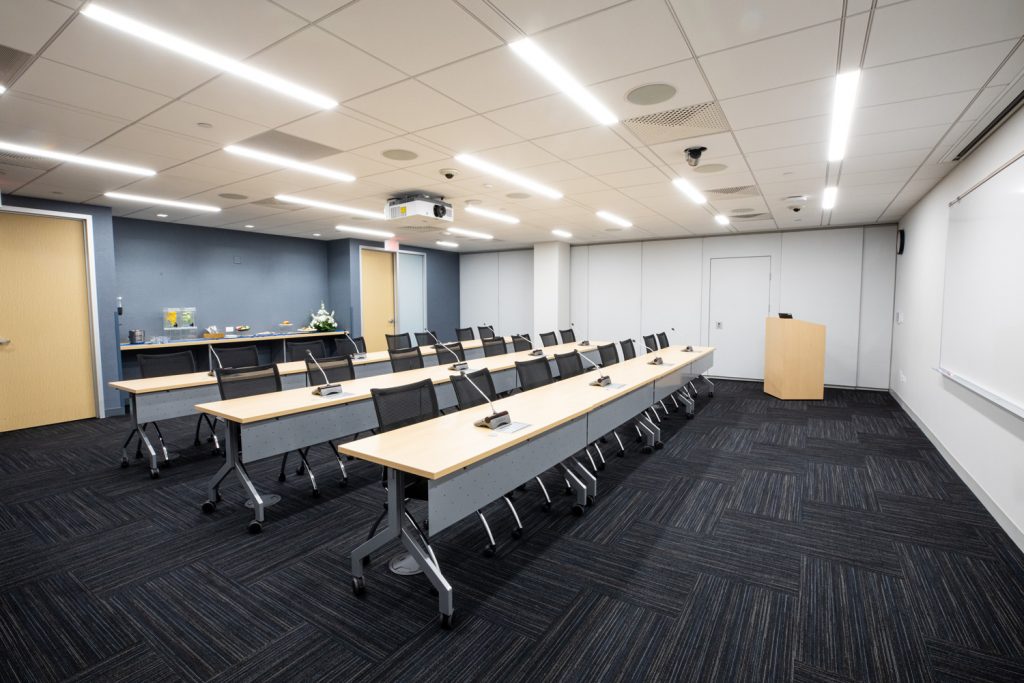 Conference Room 3A at One Rotary Place. Photo of a large conference room with tables & chairs, a podium, and a whiteboard.